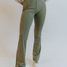Front view of model wearing the Forget It Ribbed Pants that have olive green ribbed fabric, an elastic waistband, and flared legs.