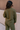 Back view of model wearing the Aria Olive Green Pattern Lounge Top which features olive green knit fabric, a monochrome geometric quilted pattern, a round neckline, and long balloon sleeves with cuffs.
