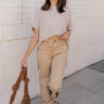 Full body front view of model wearing the Rooted Denim: Morgan Light Mustard Straight Leg Jeans that have pale mustard/brown denim fabric,  pockets, and a frayed hem.