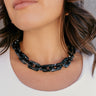 Close up of model wearing the Kendall Black Chain Link Statement Necklace that has square shaped links with a black and white marble design and a gold adjustable link closure.