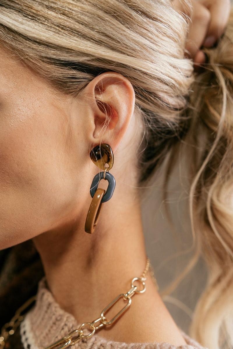 Side view of model wearing the Naomi Neutral Link Earrings that feature dark olive tortoise studs attached to grey and light brown oval chain links.