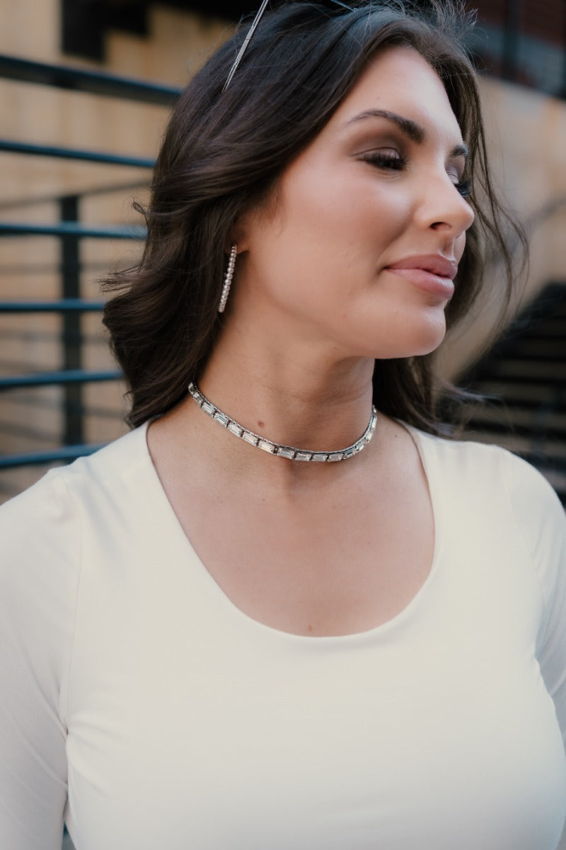 Model is wearing the Londyn Silver Rhinestone Choker that features rectangular clear rhinestones set in silver and an adjustable hook/chain closure.
