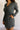 Close front view of model wearing the Ezra Grey Green Long Sleeve Romper that has grey green knit fabric, pockets, an elastic waist, a front zipper, a hood, a skirt with fitted shorts , and long sleeves.