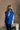 Front view of model wearing The Laurel Royal Blue Button-Up Puffer Vest features cobalt blue nylon puffer fabric, intertwined design, monochrome button up closure, high neckline and sleeveless.