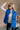 Front view of model wearing The Laurel Royal Blue Button-Up Puffer Vest features cobalt blue nylon puffer fabric, intertwined design, monochrome button up closure, high neckline and sleeveless.