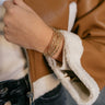 Close up view of model wearing the Ciara Twisted Gold Layered Bracelet which features gold bangle with twisted details.