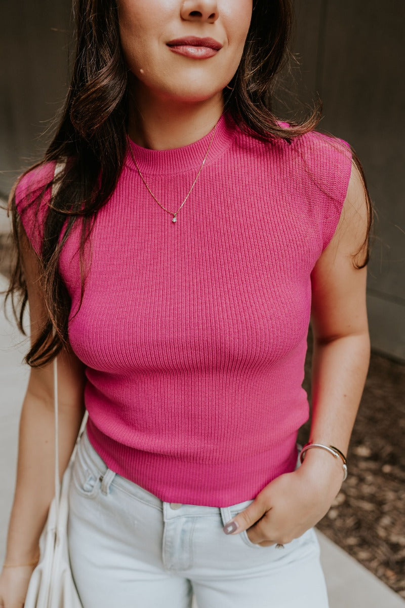 Close front view of model wearing the Veronica Hot Pink Sleeveless Sweater that has hot pink knit fabric, a ribbed hem, a round neckline and a sleeveless design.