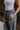 Upper side view of model wearing the Kelly Blue Wide Leg Drawstring Pants that have blue denim-washed light weight fabric, two front slit pockets, an elastic waistband with a drawstring tie, and wide pant legs.