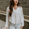 front view of model wearing the Elisabeth White Gauze Long Sleeve Button Up Top that has off white textured fabric, wooden buttons, a collar, stitched hem details and long sleeves.