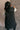 Back view of model wearing the Camryn Black Longline Puffer Vest features black puffer fabric, midi length, pockets, a hidden zipper with snap closures, a high neck, and a hood with drawstring ties.