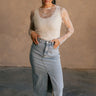 Full body front view of model wearing the Liana Denim Front Slit Midi Skirt that has light wash denim fabric, brown stitching, midi length, a raw hem, and a front slit.