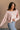 front view of model wearing the Charlotte Light Pink Raglan Sweatshirt that has light dusty pink knit fabric, raw hem details, a round neckline, and long wide sleeves.
