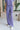 Front view of model wearing the Wanderlust Pants that feature purple plisse fabric, an elastic waistband, and wide legs with lettuce trim