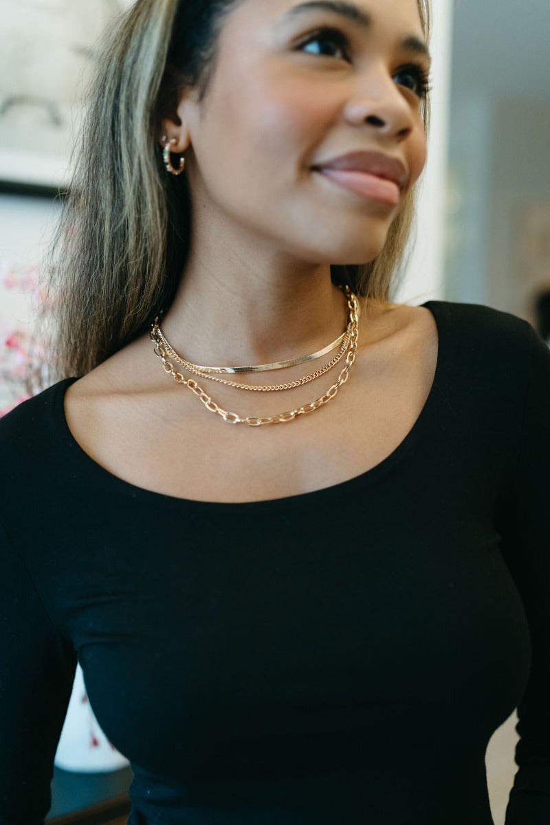 Front view of model wearing the Love Endlessly Triple Layer Necklace which features triple layer with gold chain links and flat layer.
