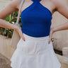 front view of model wearing The Azure White Denim Ruffle Mini Skirt features off white denim fabric, shorts lining, mini length, a ruffled skirt overlay, a flared skirt hem, and a side zipper closure.