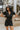 Front view of model wearing the Dakota Denim Romper in Black that has black denim fabric, front pockets, a hidden front zipper, a collared neckline, a monochromatic belt at the waistline, and short sleeves