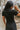 Close back view of model wearing the Dakota Denim Romper in Black that has black denim fabric, front pockets, a hidden front zipper, a collared neckline, a monochromatic belt at the waistline, and short sleeves