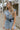 Front view of model wearing the Are You Ready Romper that has washed lightweight denim fabric, front pockets, two back pockets, a hidden front snap closure, a collar, short sleeves, and  frayed hems.