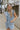 Front view of model wearing the Are You Ready Romper that has washed lightweight denim fabric, front pockets, two back pockets, a hidden front snap closure, a collar, short sleeves, and  frayed hems.