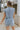 Back view of model wearing the Are You Ready Romper that has washed lightweight denim fabric, front pockets, two back pockets, a hidden front snap closure, a collar, short sleeves, and  frayed hems.