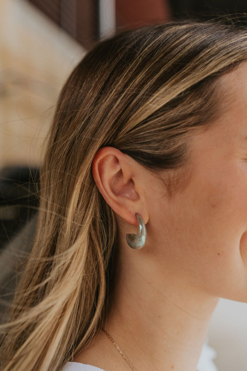 Close up view of model wearing the Float Away Earrings which features multi, iridescent open mini shaped hoops.