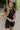 Front view of model wearing the Bring It On Romper that has black stretchy fabric, a romper body, a monochromatic front zipper, a round neckline, and short sleeves.