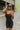 Front view of model wearing the Call It Even Romper that features black stretch fabric, a romper body, a round neckline, bra padding, and adjustable spaghetti straps.