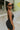 Side view of model wearing the Call It Even Romper that features black stretch fabric, a romper body, a round neckline, bra padding, and adjustable spaghetti straps.