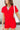 Close up view of model wearing the Dakota Denim Romper in Red which features red denim fabric, front pockets, a hidden front zipper, a collared neckline, a monochromatic belt at the waistline, and short sleeves.