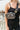 Model is wearing the Victoria Clear Sling Bag in Black that has clear fabric with black trim, a black adjustable strap with gold hardware, and a gold zipper closure.