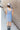 Full body back view of model wearing the Long Beach Dress that has light blue ribbed fabric, midi length, a round neckline, and thick straps.