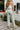 Back view of model wearing the Cross Road Jeans in Mint Green which features light sage green denim fabric, two front pockets, two back pockets, a front zipper with a monochromatic button closure, belt loops, wide legs and raw hems.