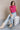 Front view of model wearing the Kelly Pink Cropped Turtleneck Sweater which features hot pink cable knit fabric, a cropped waist, a turtleneck neckline, and a sleeveless design.