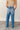 back view of model wearing the Ceros: Billie Wide Leg Paper Bag Jeans that have medium wash denim fabric, pockets, a front zipper, belt loops, an elastic paperbag waist, and wide legs with raw hems.
