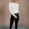 Full body front view of model wearing the Norah Off White Mock Neck Top that has off white ribbed fabric, a high neckline, and long sleeves.