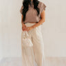 Full body front view of model wearing the Scarlett Beige Wide Leg Pants that have light beige lightweight fabric, two front pockets, a front zipper with a hook closure, belt loops, and wide legs.