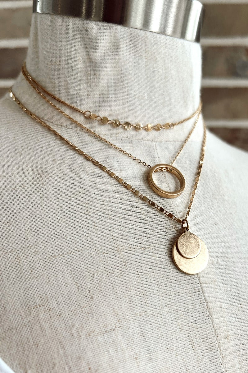 Close up view of the With You Necklace in Gold which features small gold chain links, triple layered and two full circles with an open circle attachment.