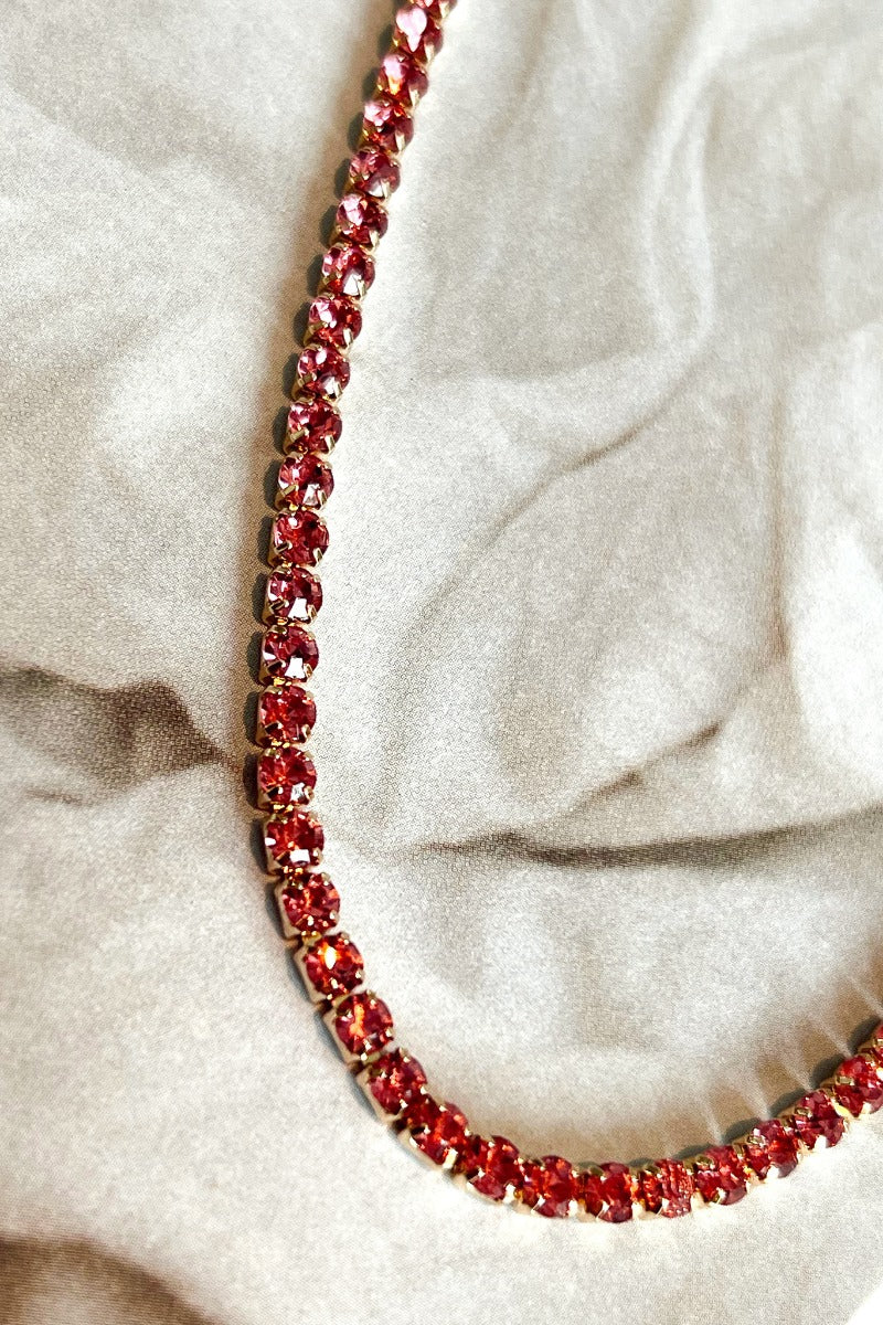 Close up view of the Make Me Blush Necklace which features pink stones set in gold.