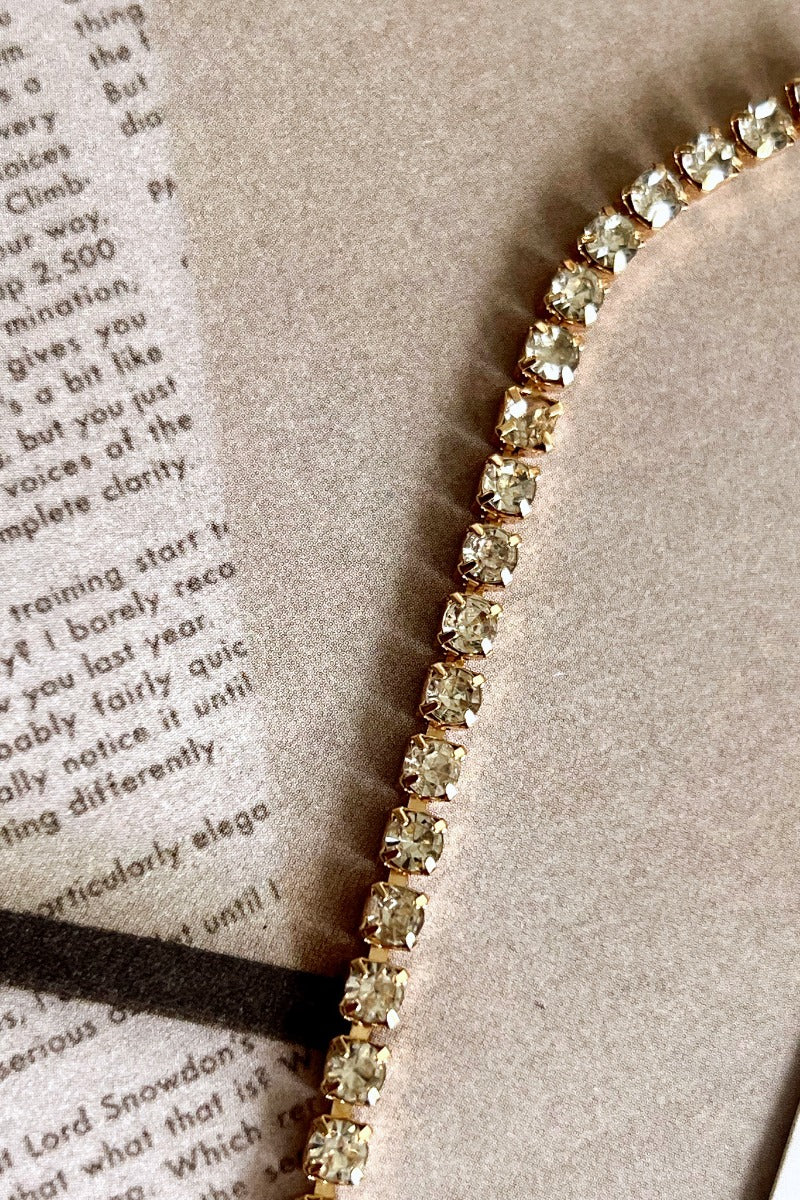 Close up view of the Full of Class Necklace which features one layer of clear stones set in gold.