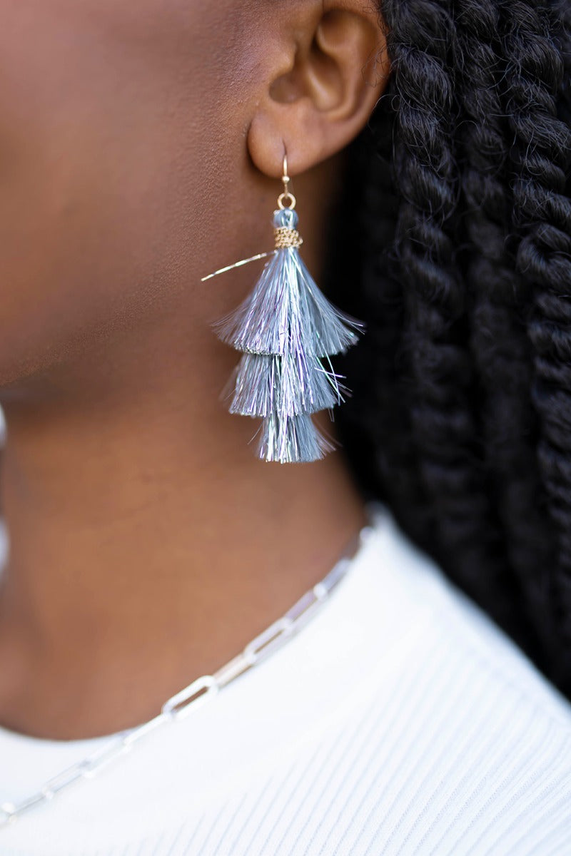 Close up view of model wearing the Let's Party Earrings in Silver which features silver metallic tassels.
