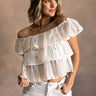 front view of model wearing the Carolina Ivory Tiered Floral Top that has ivory light weight fabric, a three tiered design, multi color embroidered flower details, a square neckline and ruffle straps.