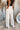 Back view of model wearing the Isabella Corduroy Pants, that feature lightweight cream-colored corduroy, a button + zipper closure, front and back pockets, and wide legs