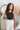 Upper front view of model wearing the Isabella Corduroy Pants, that feature lightweight cream-colored corduroy, a button + zipper closure, front and back pockets, and wide legs