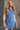 Front view of model wearing the Regina Blue Denim Sleeveless Dress which features blue denim fabric, button up, two front buttoned chest pockets, collared neckline and sleeveless.