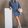 Full body view of model wearing the Tessa Blue Denim Long Sleeve Mini Dress which features blue denim fabric, front button up, collared neckline, two front chest buttoned pockets, brown stitching details and long sleeves with buttoned cuffs.