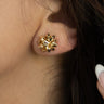Close-up view of model wearing the Cora Gold Bow Stud Earrings that feature small gold studs shaped as a present bow.
