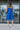Full body back view of model wearing the Summer Shade Romper that has cobalt blue fabric, a two-tiered body, a scooped neckline, and tie straps.