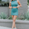 Full body front view of model wearing the Get Obsessed Skort in Teal that has teal fabric, a mini length hem, shorts lining, and an overlapped waistline.