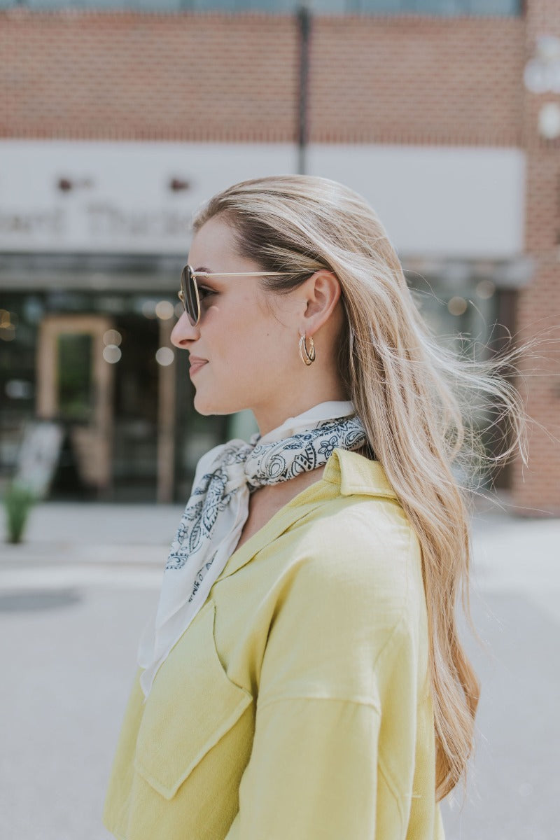 Side view of model wearing the Shine On Earrings which features small, closed hoops with three layers and hammered design.