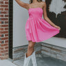 Full body view of model wearing the Call It Love Mini Dress which features pink fabric, mini length, pink lining, upper pleated design, a strapless neckline, and a monochromatic back zipper with hook closure.